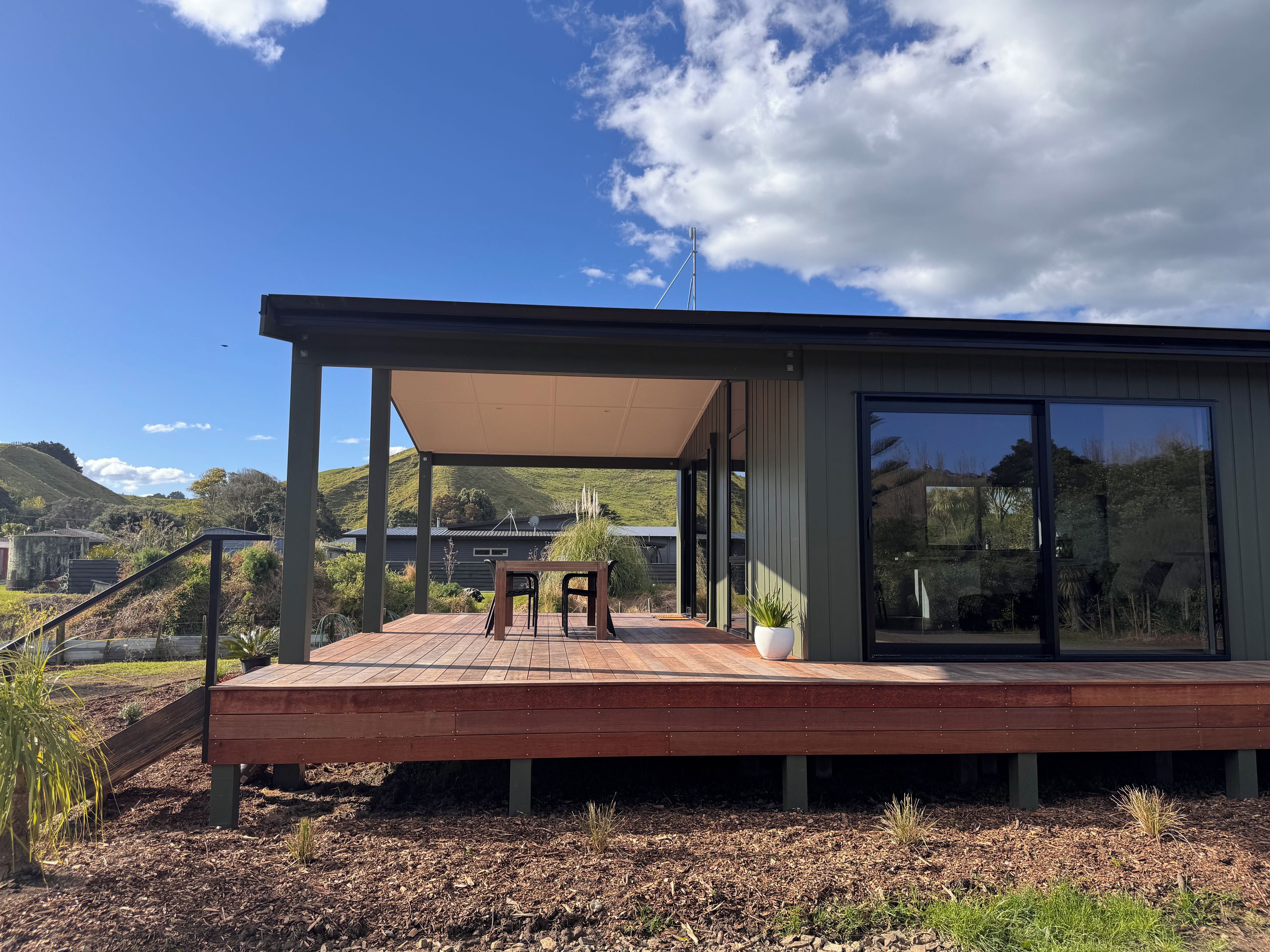 A modern house with a wooden deck, a covered patio, and a large glass window.