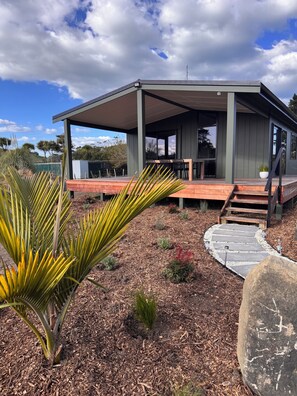 A modern house with a covered patio, outdoor seating, and a stone pathway leading to the entrance.