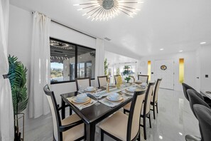 Un espace repas moderne avec une longue table dressée pour six personnes, entourée de chaises.