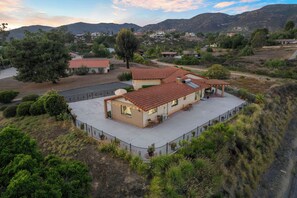Une maison avec un toit recouvert de tuiles rouges, un patio abrité et une cour clôturée.