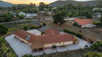 Zona residencial com casas com telhados vermelhos, cercada por vegetação e colinas ao fundo.
