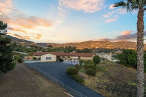 A residential area with a house featuring a fenced driveway, a garage, and a well-maintained lawn.