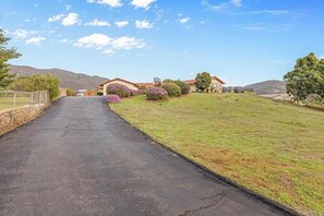 A residential driveway leading to a house with a well-maintained lawn and flowering bushes. - Mountain View, 2500 sqft, King Bed, Garage, 3BR/2Bth (Jamul)
