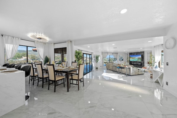A spacious living area with a dining table, chairs, a sofa, and a TV.