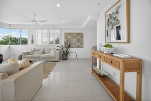 A modern living room with a sofa, a wooden console table, and a ceiling fan. - Soul@Sunshine - Private Pool, Ocean View (Sunshine Beach)
