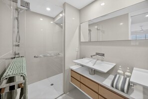 A modern bathroom with a glass shower enclosure, a white sink, and a large mirror. - Soul@Sunshine - Private Pool, Ocean View (Sunshine Beach)