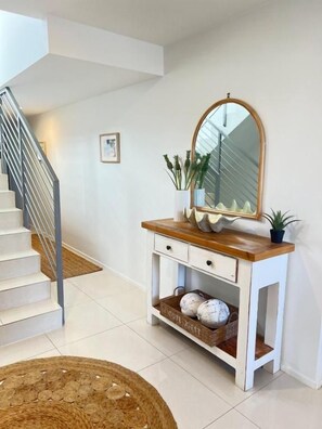 A staircase leading to an upper floor, a white console table with a mirror, and a wicker basket on the floor. - Soul@Sunshine - Private Pool, Ocean View (Sunshine Beach)