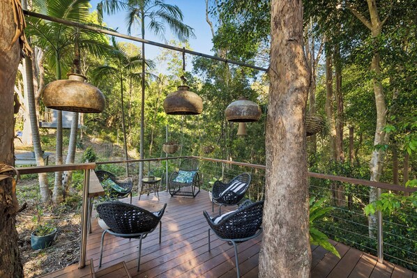 An outdoor deck with wooden flooring, metal railings, and wicker chairs. - Studio Jindi (Nunderi)