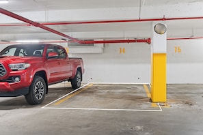 A red pickup truck parked in a parking space marked with numbers 74 and 75, indicating a multi-level parking structure. - Elegant Skyline Retreat | 2BR•UG Parking (Edmonton)