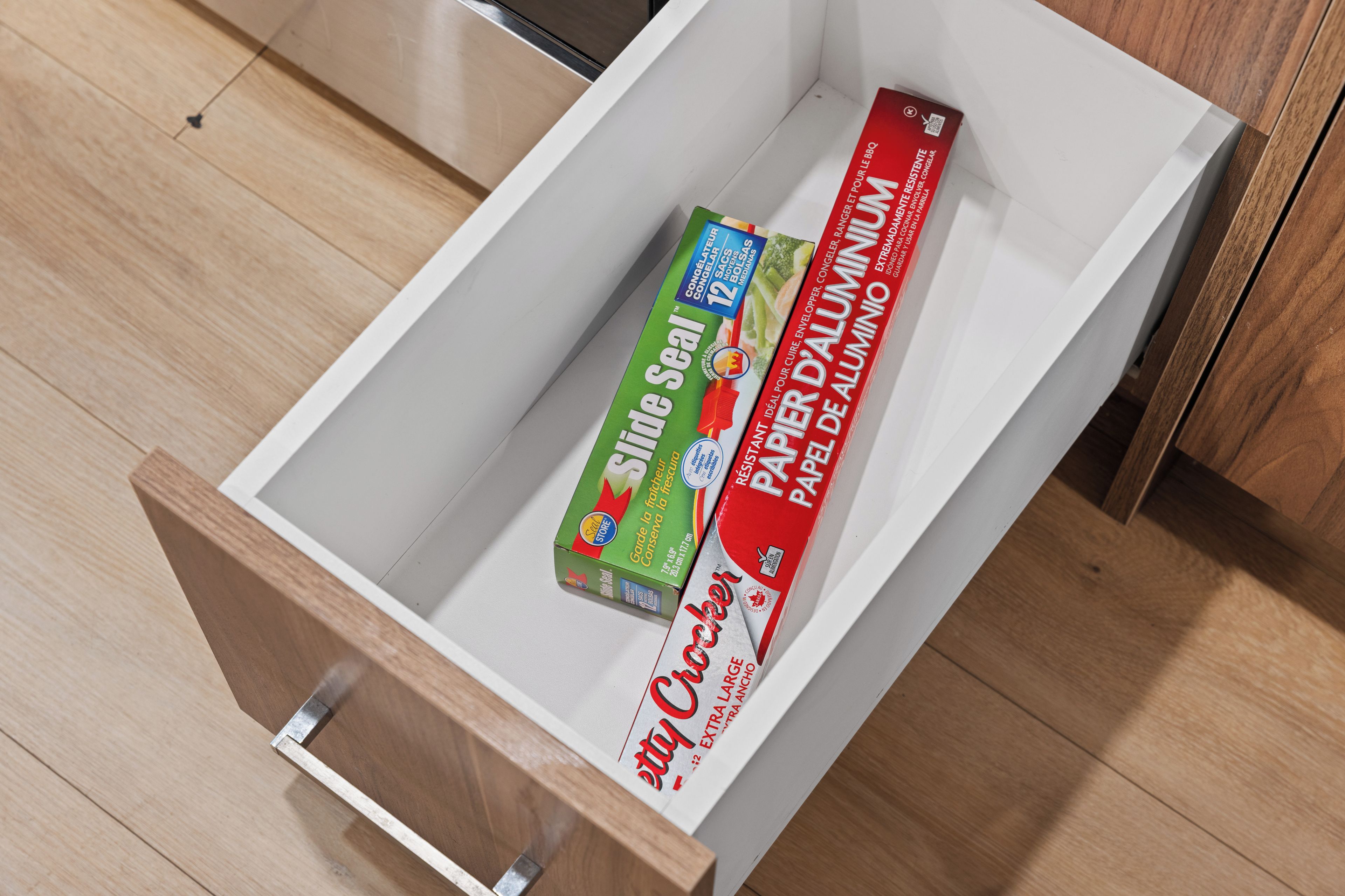 Un tiroir contenant un paquet d’essuie-tout de la marque « Selle » et une bouteille de soda de la marque « Coca-Cola ».