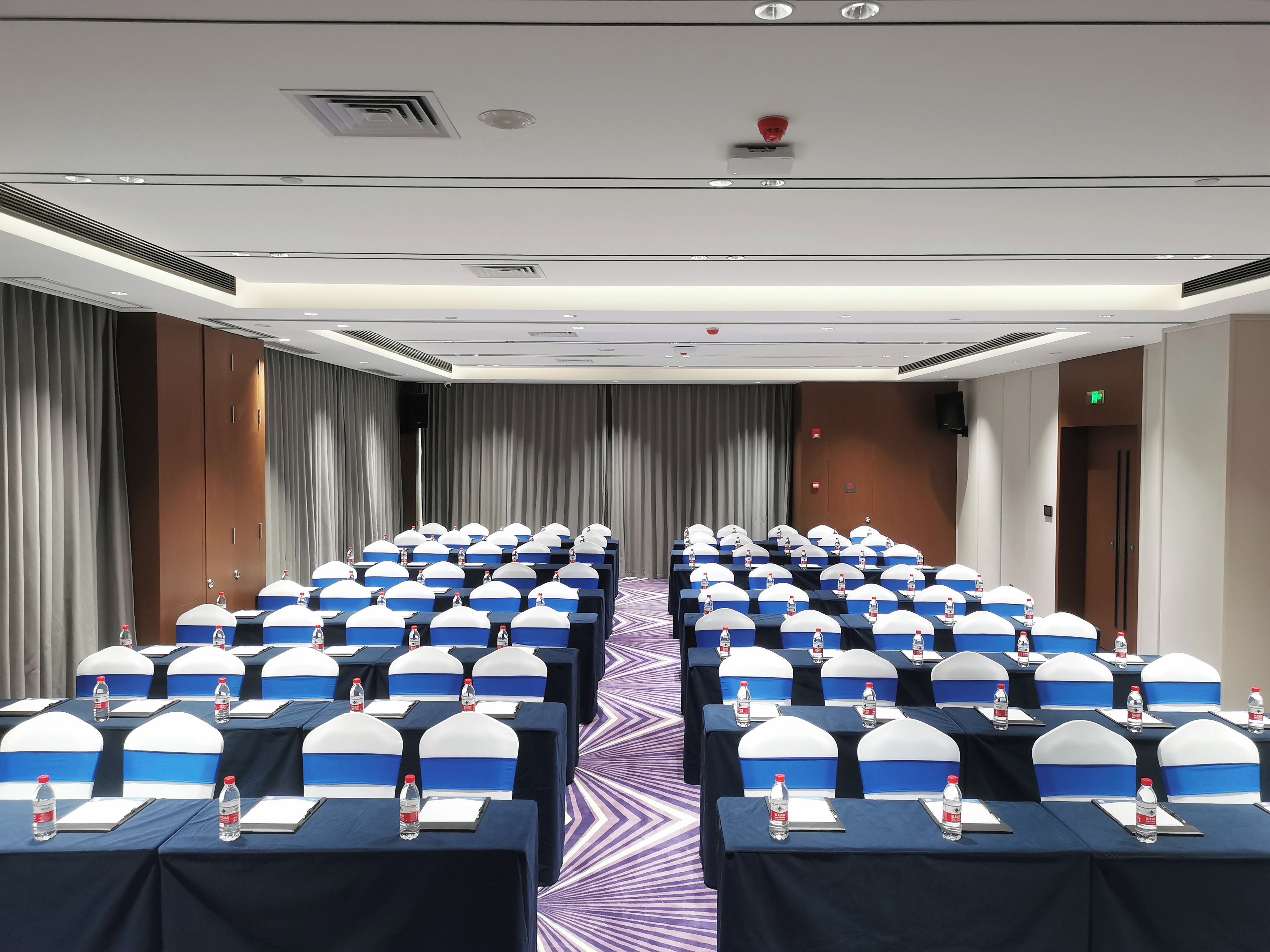 A conference room with rows of tables, each with a water bottle and notepad.