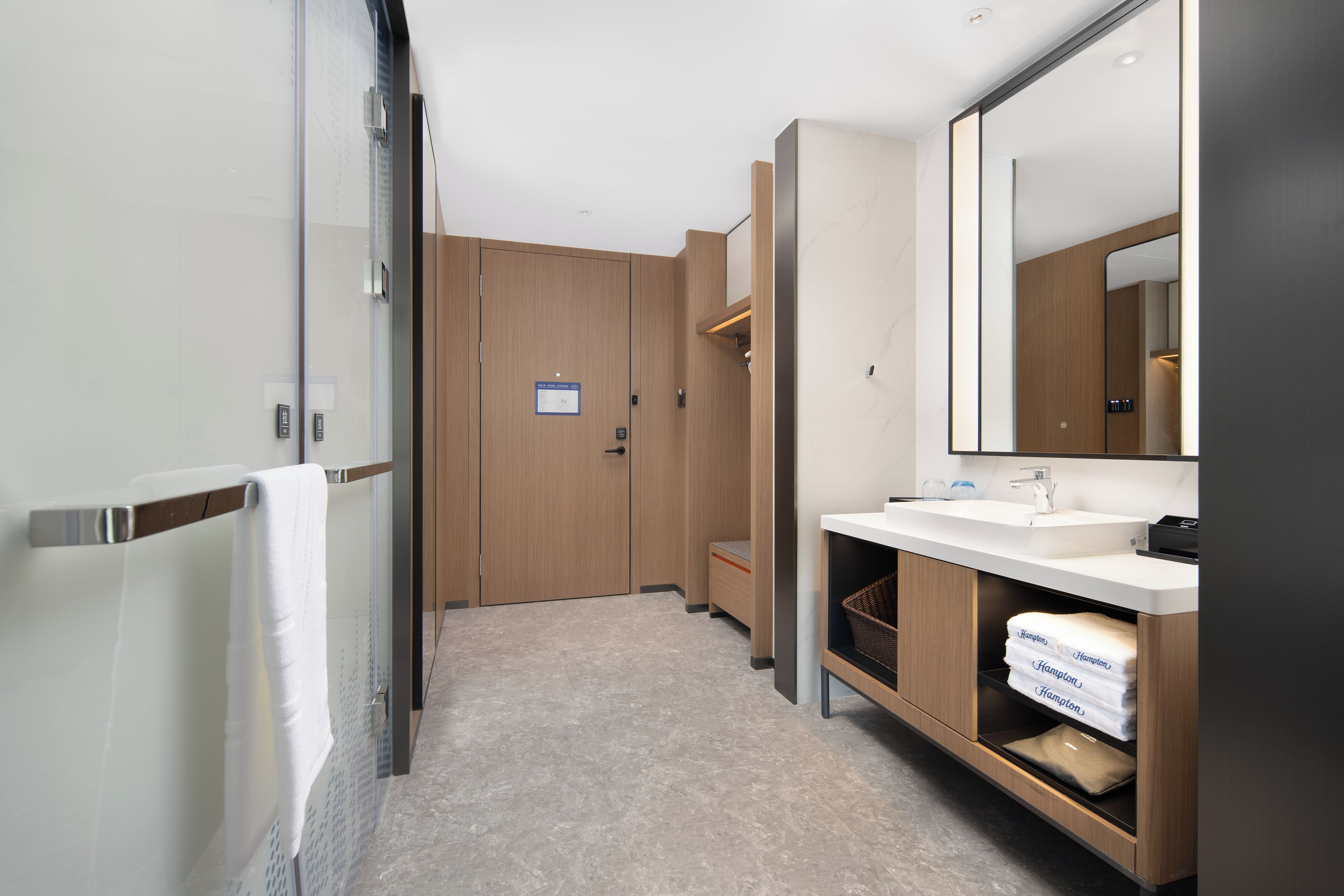 A modern bathroom with a large mirror, two sinks, a shower area, and a toilet.