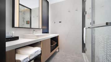A modern bathroom with a large mirror, a sink, and a shower area.