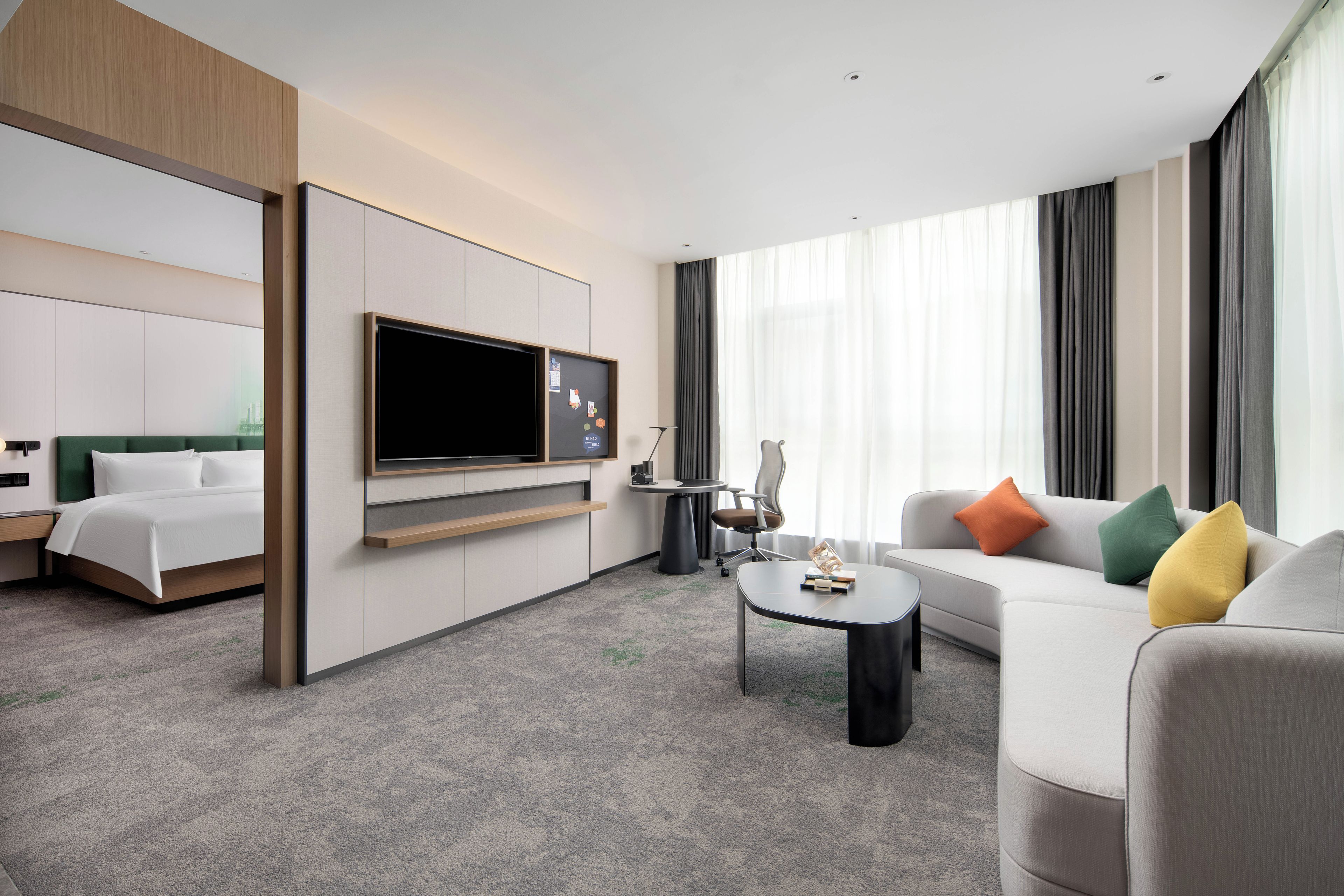 Habitació d'hotel moderna amb un llit, un sofà, una taula de cafè, una televisió i un escriptori.