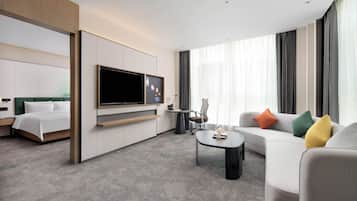 Habitació d'hotel moderna amb un llit, un sofà, una taula de cafè, una televisió i un escriptori.