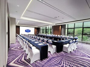 A conference room with a long table, chairs, and a presentation screen.