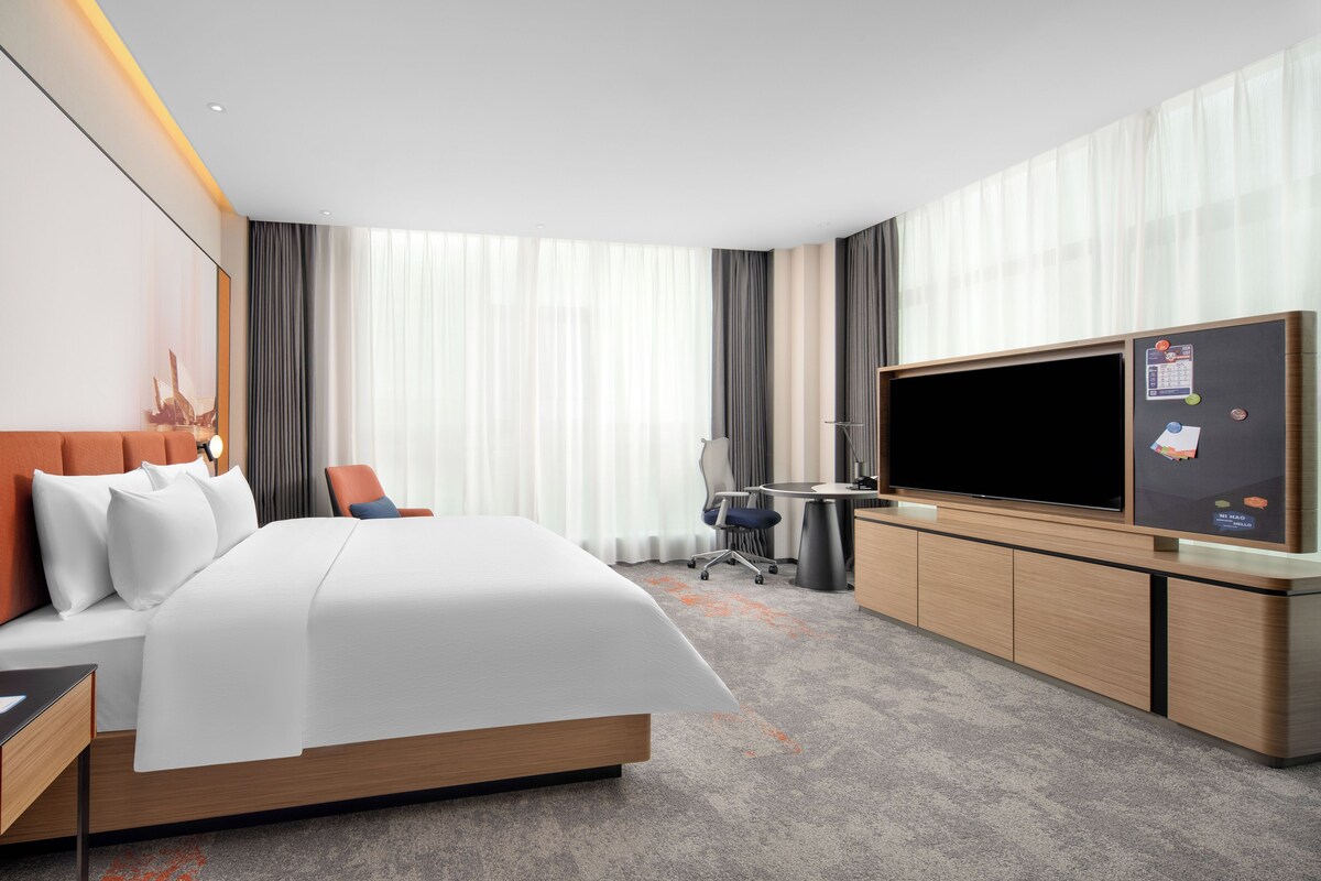 Une chambre d’hôtel avec un grand lit, un bureau, une télévision et une vue sur la ville.