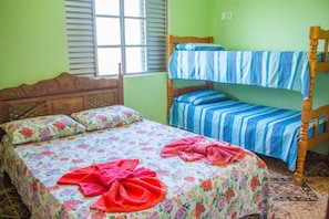 Une chambre avec un lit en bois, un lit superposé et une fenêtre avec des stores.