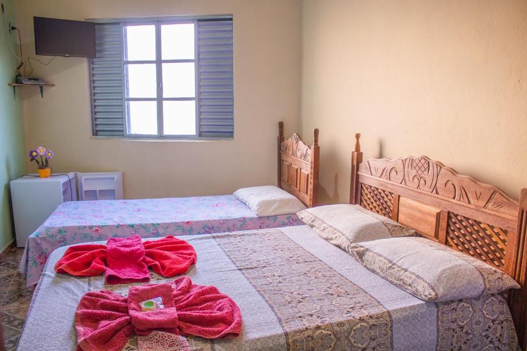 A bedroom with two beds, a television on the wall, and a window with shutters.