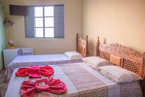 Une chambre avec deux lits, un téléviseur fixé au mur et une fenêtre avec des volets.