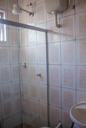 Une salle de bain avec une douche à parois de verre, des murs carrelés et un lavabo.