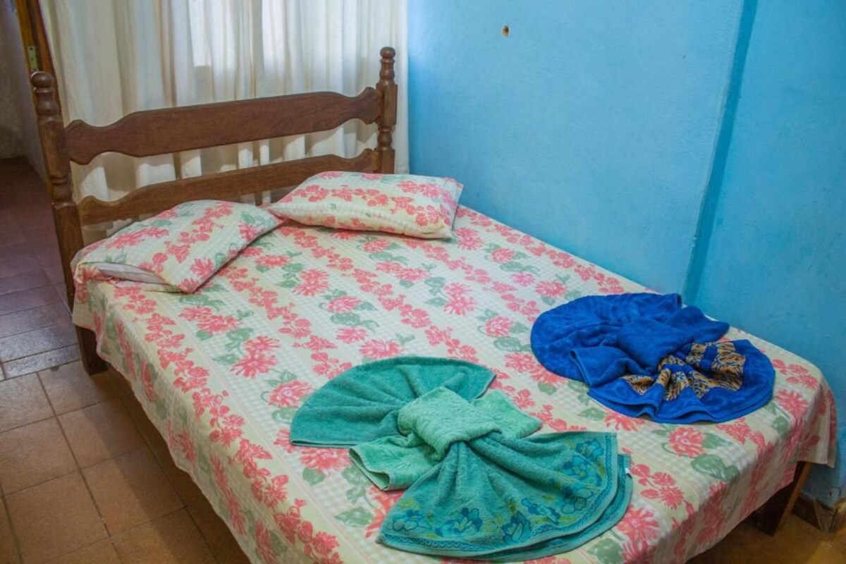 Un lit avec une literie à motifs floraux, une tête de lit en bois et un mur bleu.