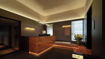 A modern reception area with a wooden reception desk, a seating area, and a large window providing natural light.