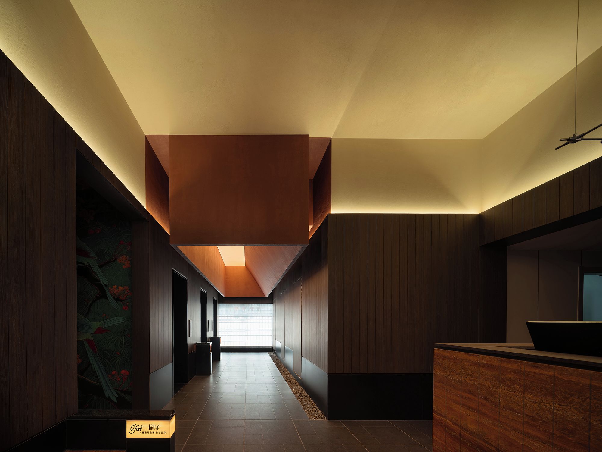 A modern interior with a long hallway, wooden paneling, and a reception desk.