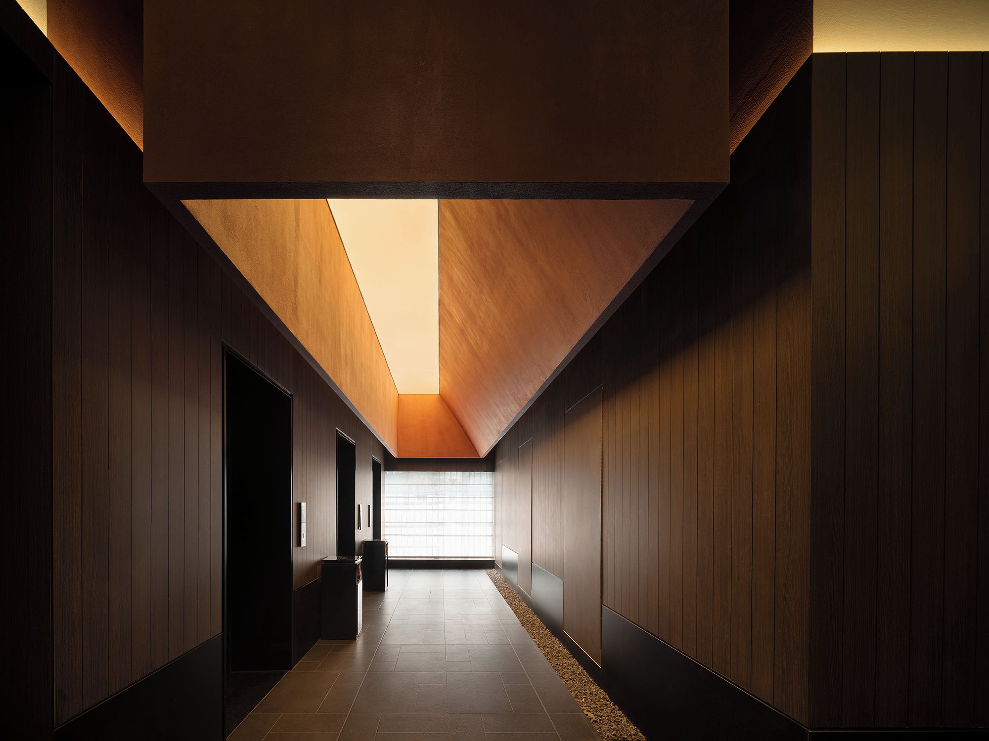 A corridor with wooden panel walls and a sloped ceiling.