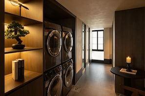 A laundry room with multiple washing machines, a bonsai tree, and a candle on a table. - Ufeel Hotel Canton Tower & Pazhou Branch (Guangzhou)