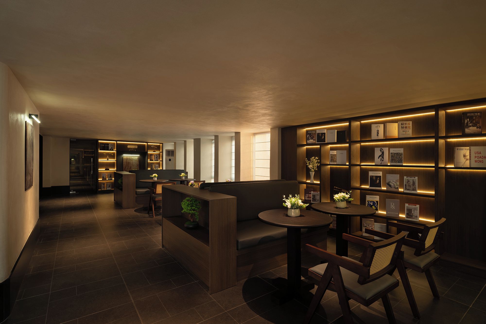 Een moderne hotelentree met een receptiebalie, een zithoek en een muur met ingelijste foto's en prijzen.