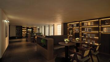 A modern hotel lobby with a reception desk, seating area, and a wall displaying framed photographs and awards.