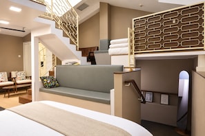 A modern hotel room with a bunk bed, a sofa, a staircase, and a view of the city. - Aura Hotel Purvis L2 (Singapore)