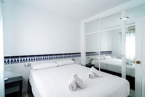 A hotel room with a bed, a bedside table, a mirror, and a wardrobe. - Apartment in Nerja Near Burriana Beach (Nerja)