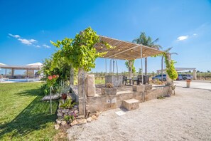 A covered outdoor seating area with a pergola, surrounded by greenery and a pool in the background. - Trullo Mary Relax&Heated Pool, Carpignano Salentino, Italy (Carpignano Salentino)