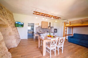 A compact living space with a dining area, kitchenette, and a bunk bed. - Trullo Mary Relax&Heated Pool, Carpignano Salentino, Italy (Carpignano Salentino)