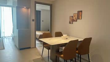 Ett modernt hotellrum med en matplats, en säng och en hall som leder till ett annat rum.