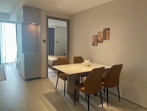 Une chambre d’hôtel moderne comprenant un coin repas, un lit et un couloir menant à une autre pièce.