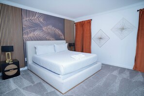 A neatly arranged bedroom with a bed, a nightstand, a lamp, and decorative wall art. - 6BR Pool Home w/ Theater & Game Room (Davenport)