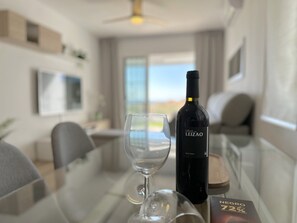 A bottle of Vinas de Leizao wine and a glass on a table in a modern living room with a view of the outdoors. - Apartment in Nerja With Pool and Tennis Court (Nerja)