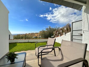 A balcony with two chairs, a small table, and a potted plant. - Apartment in Nerja With Pool and Tennis Court (Nerja)