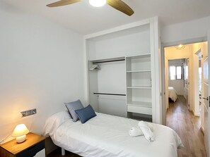 A bedroom with a bed, bedside table, lamp, and a walk-in closet with shelves. - Apartment in Nerja With Pool and Tennis Court (Nerja)