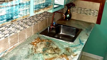 A kitchen with a sink, a faucet, and a backsplash with a distressed tile pattern.