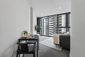 A modern apartment with a dining area, a sofa, and large windows offering a view of high-rise buildings. - The Southbank King - Pool, Gym and Tram, near CBD (Southbank)