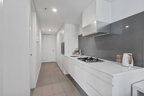 A modern kitchen with white cabinetry, a gas stove, and a stainless steel range hood. - The Southbank King - Pool, Gym and Tram, near CBD (Southbank)