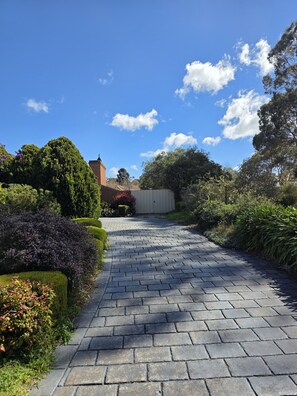 A paved pathway leading through a landscaped garden with various shrubs and trees. - 🌿 Private Queen Bedroom, Private Bathroom & Garden Retreat in Sunbury (Sunbury)