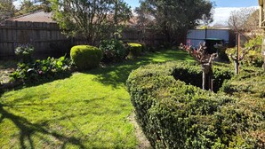 Un jardin bien entretenu, agrémenté de divers arbustes et d’une pelouse soigneusement taillée.