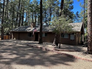A single-story house with a sloped roof, surrounded by tall pine trees. - 3-Bedroom Ponderosa Paradise at 6,398 feet. Beautifuly cool. (Prescott)