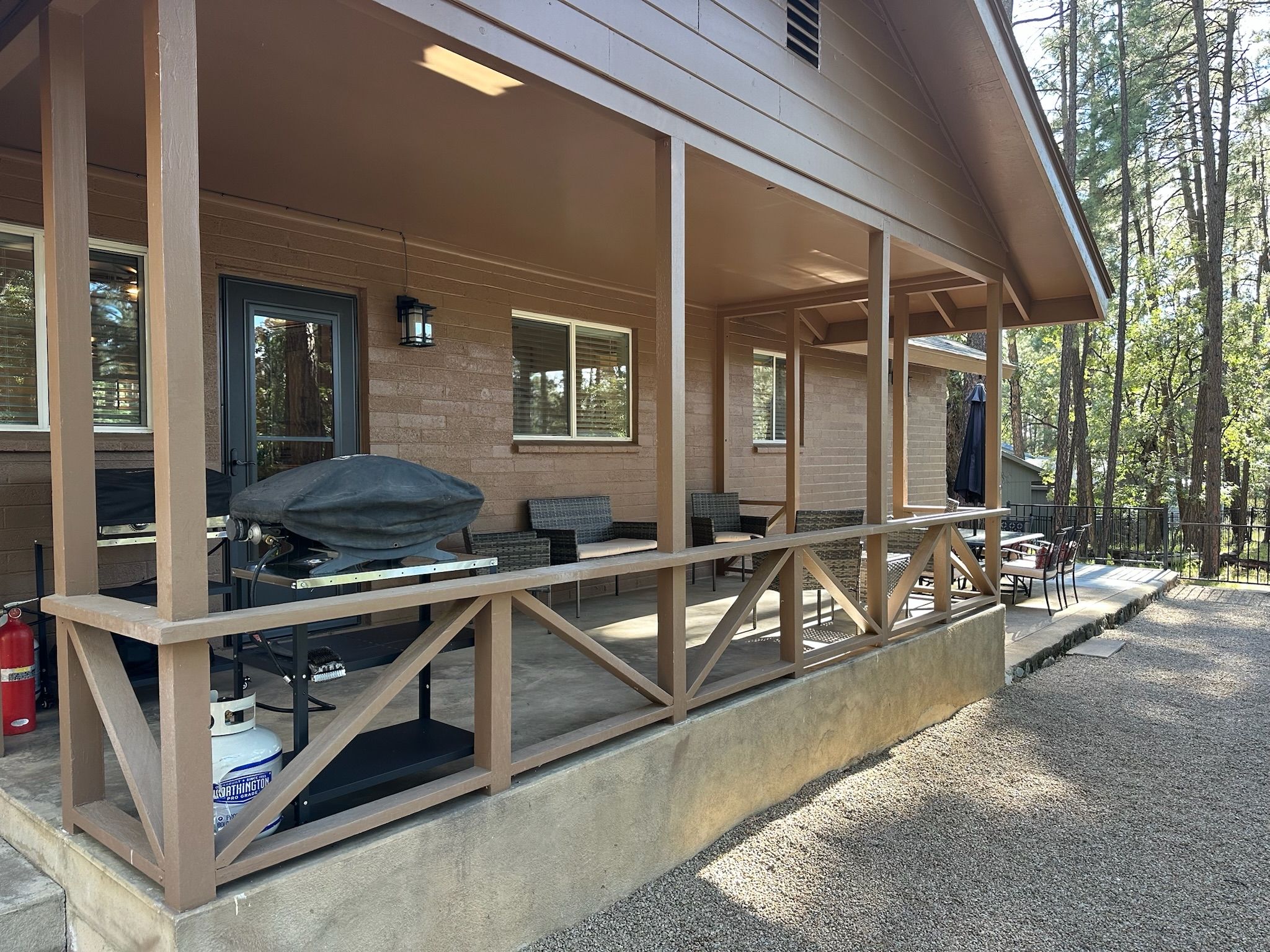 A covered outdoor area with a barbecue grill, seating, and a fire extinguisher.