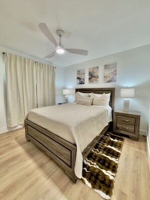 Ein Schlafzimmer mit einem Bett, einem Deckenventilator, einem Nachttisch und einem Teppich.